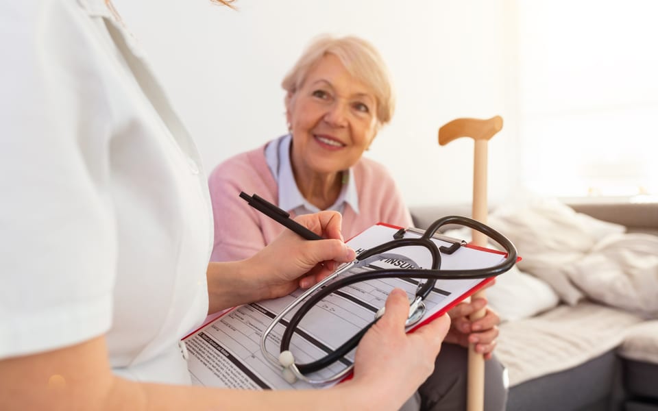 Caregiver supporting an older adult in a bright, comfortable home